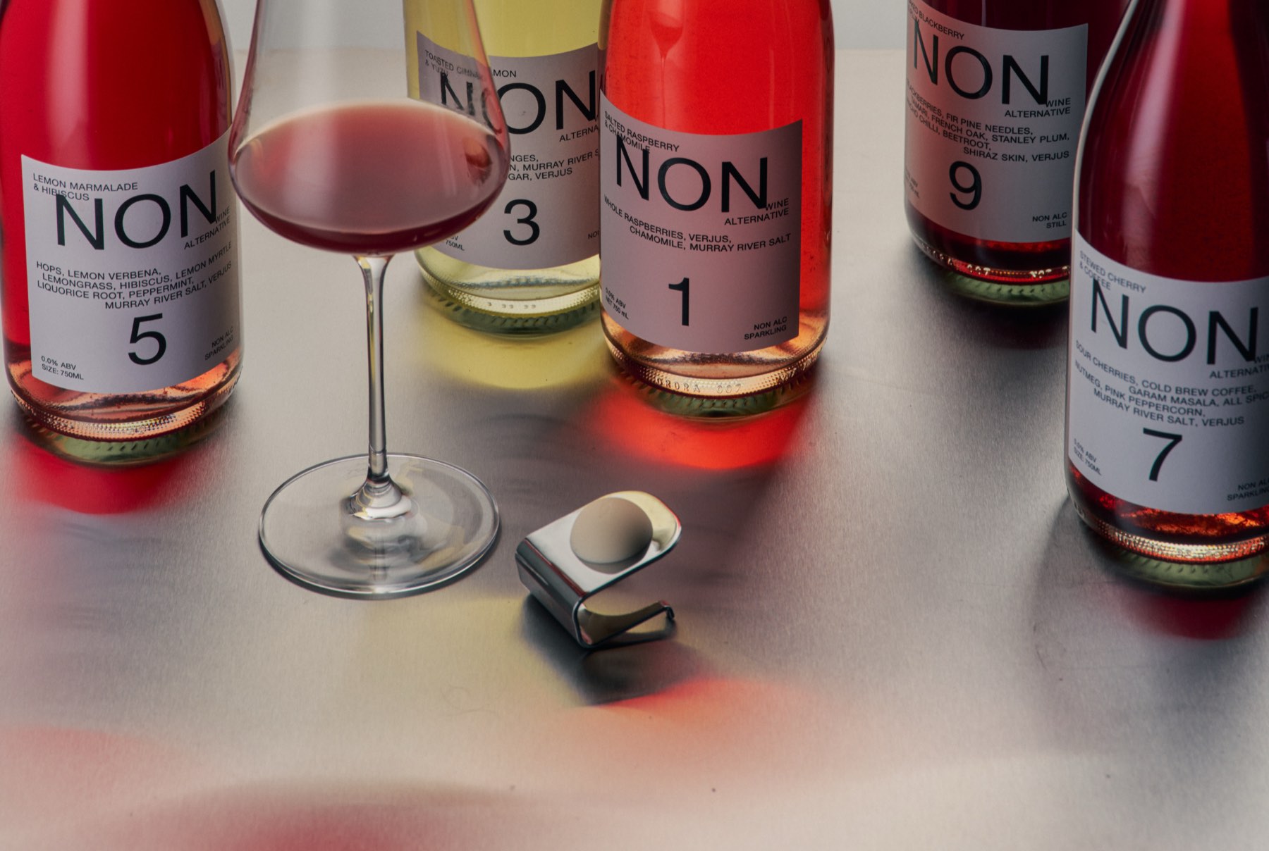 Six NON bottles and a filled wine glass on a bar top